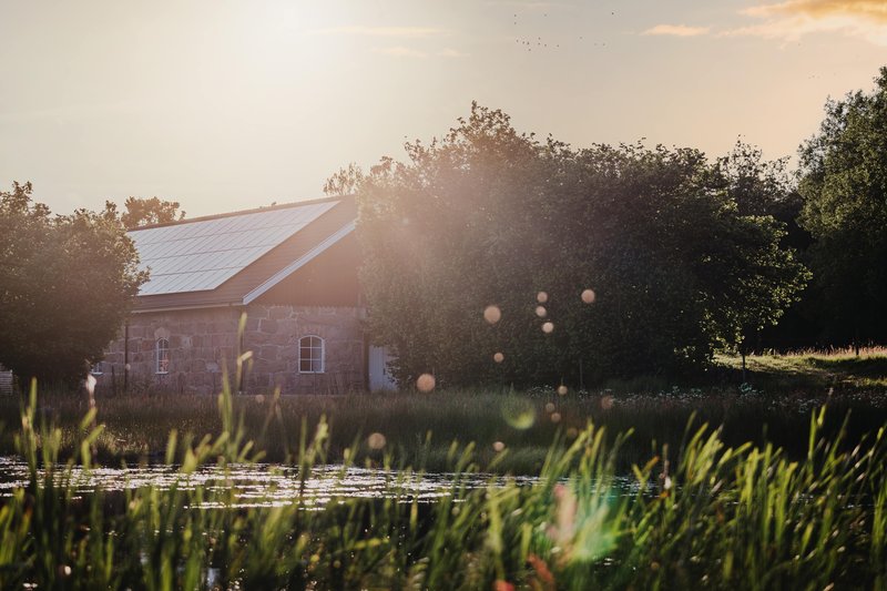 Farmhaus mit einem Teich mit Solaranlagen (wann lohnt sich eine Wärmepumpe mit Photovoltaik?).