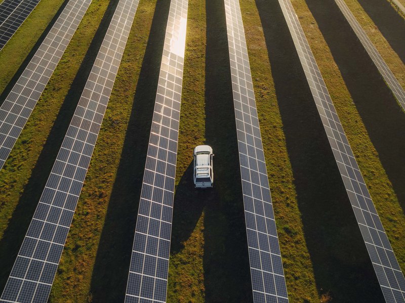 Auto fährt über ein Feld mit Photovoltaikanlagen