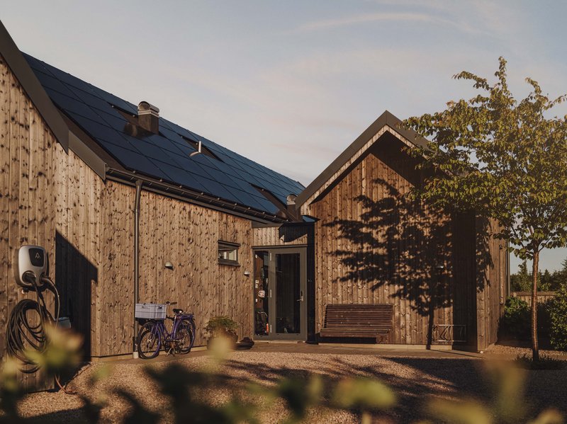 Holzhaus mit PV-Anlage und Wallbox. (Solarenergie wird immer beliebter - was sind die Vorteile von PV-Anlagen).