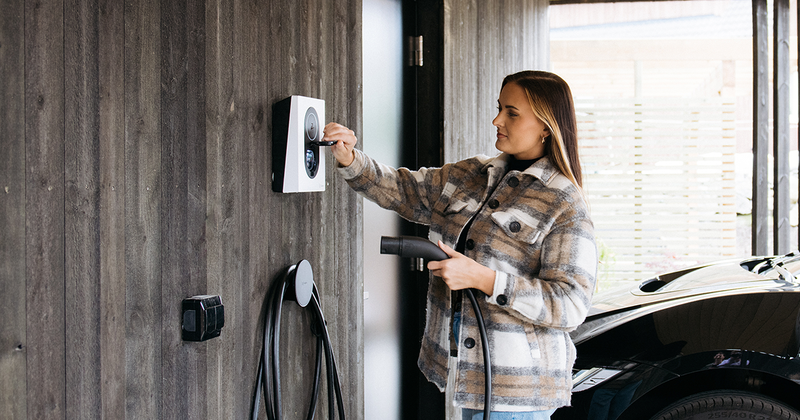 Kvinna som laddar bilen med en laddbox